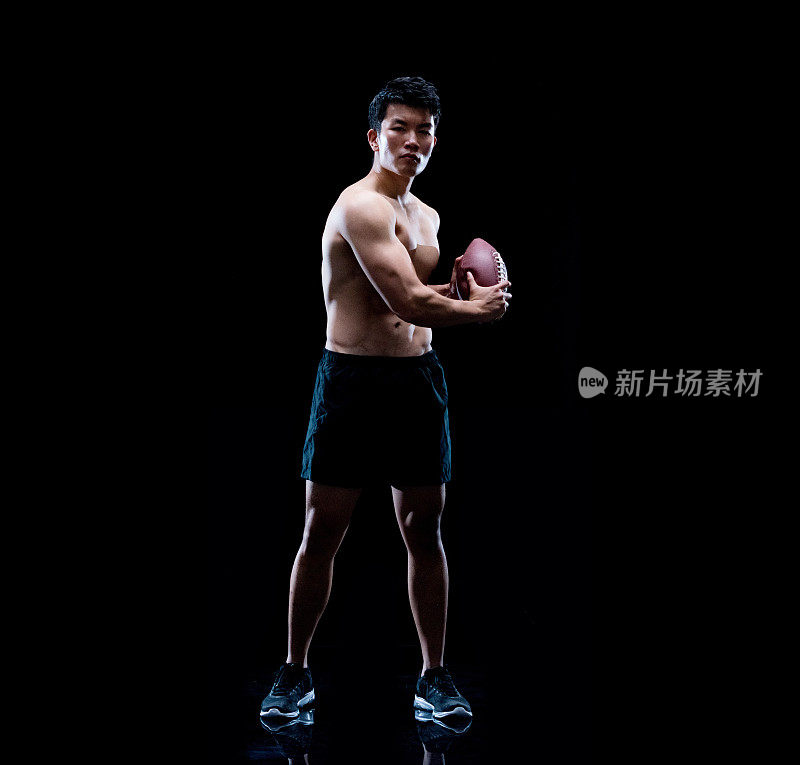 长度/一人仅/一人30-39岁的成年人英俊的人黑头发中国人/东亚民族男性/年轻男子站在黑色背景前，穿着短裤/运动鞋和使用运动球